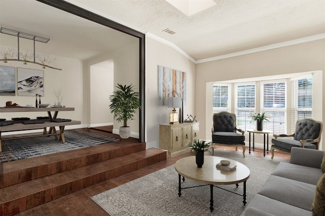 living room with a textured ceiling, hardwood / wood-style flooring, vaulted ceiling, and ornamental molding