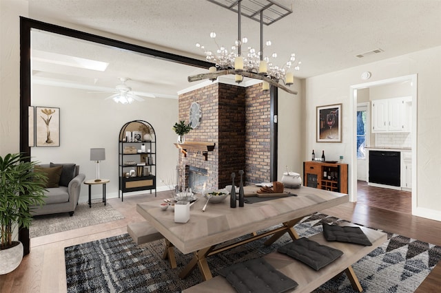 dining room featuring hardwood / wood-style floors, a fireplace, a textured ceiling, and ceiling fan with notable chandelier