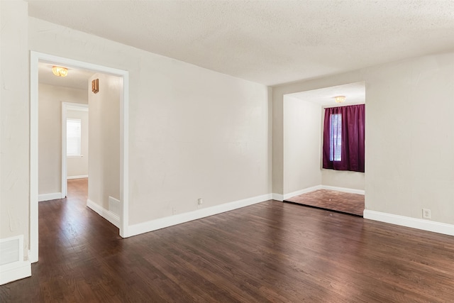 unfurnished room featuring a textured ceiling and dark hardwood / wood-style floors