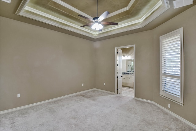 carpeted empty room with a tray ceiling, ceiling fan, and ornamental molding