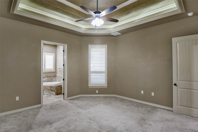 unfurnished bedroom featuring a tray ceiling, connected bathroom, light carpet, and crown molding