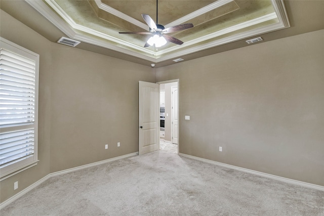 carpeted empty room with ceiling fan, ornamental molding, and a tray ceiling