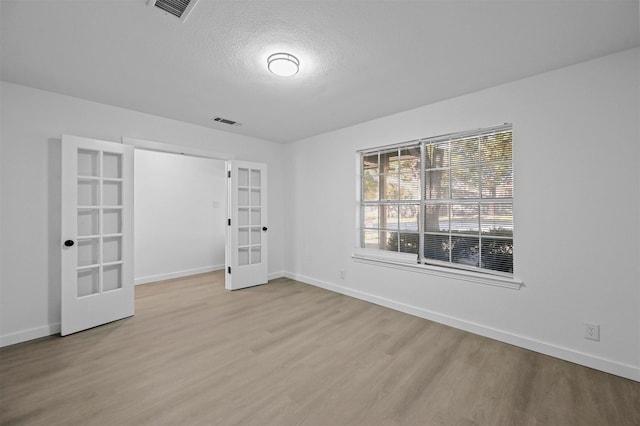 unfurnished bedroom with light hardwood / wood-style flooring, french doors, and a textured ceiling