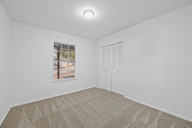 unfurnished bedroom featuring carpet, a textured ceiling, and a closet