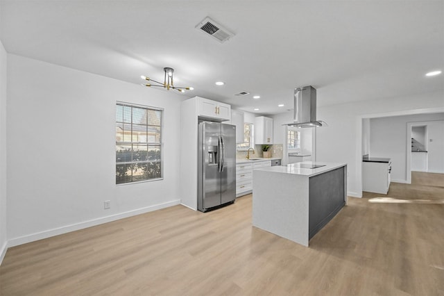 kitchen with a wealth of natural light, sink, white cabinets, island exhaust hood, and stainless steel refrigerator with ice dispenser