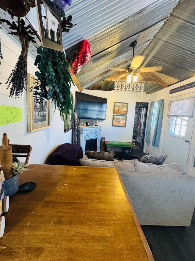 living room with a ceiling fan, lofted ceiling, and a fireplace