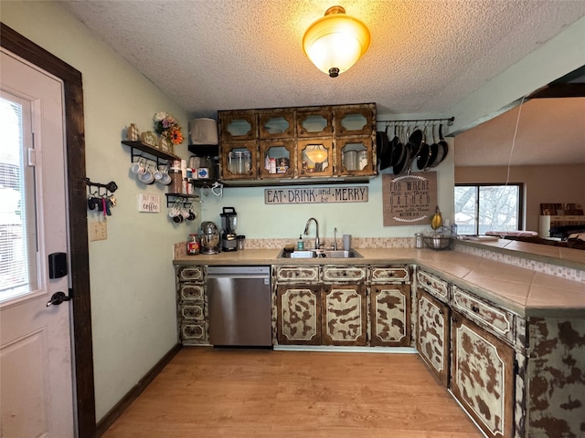 kitchen featuring sink, a textured ceiling, light hardwood / wood-style flooring, kitchen peninsula, and dishwasher