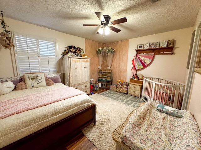 bedroom with ceiling fan, hardwood / wood-style floors, and a textured ceiling