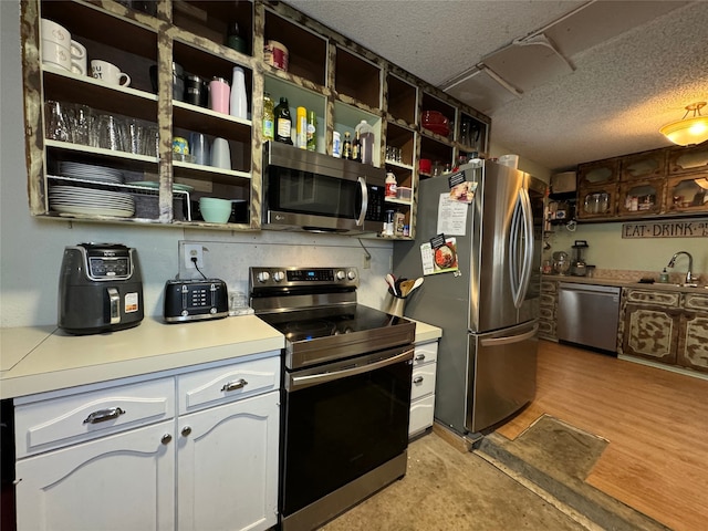 kitchen featuring sink, light wood-type flooring, white cabinets, and appliances with stainless steel finishes