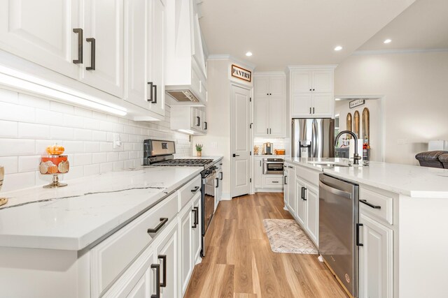 kitchen featuring custom exhaust hood, a center island with sink, sink, light hardwood / wood-style flooring, and appliances with stainless steel finishes