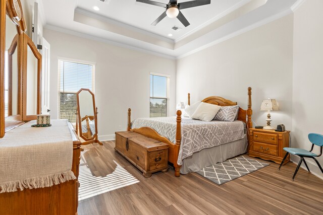 bedroom featuring hardwood / wood-style flooring, a raised ceiling, ceiling fan, and crown molding