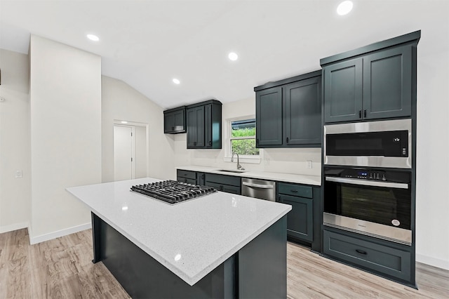 kitchen featuring appliances with stainless steel finishes, sink, light hardwood / wood-style flooring, a center island, and lofted ceiling