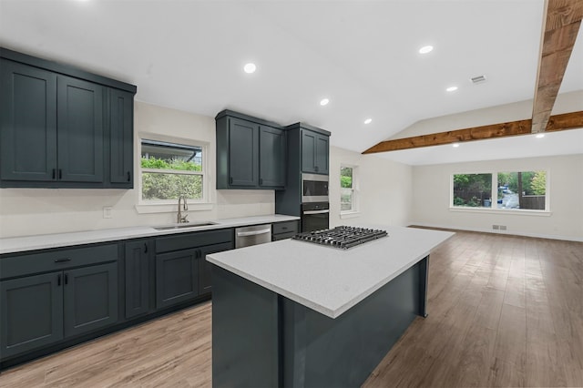 kitchen featuring stainless steel appliances, a kitchen island, a healthy amount of sunlight, and light hardwood / wood-style floors