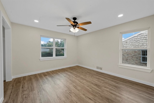 unfurnished room featuring plenty of natural light, ceiling fan, and wood-type flooring