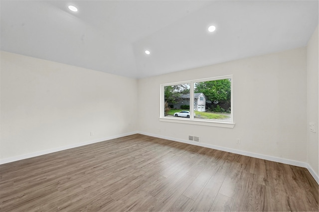 empty room with light wood-type flooring and vaulted ceiling