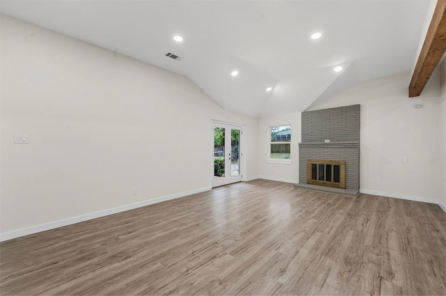 unfurnished living room featuring vaulted ceiling with beams, a fireplace, french doors, and light wood-type flooring