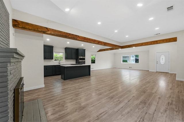 unfurnished living room featuring hardwood / wood-style flooring, plenty of natural light, and a stone fireplace