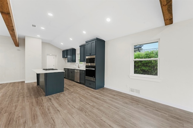 kitchen featuring appliances with stainless steel finishes, a breakfast bar, lofted ceiling with beams, light hardwood / wood-style flooring, and a kitchen island