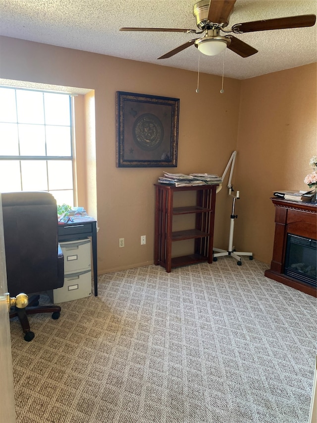 carpeted office space featuring ceiling fan and a textured ceiling