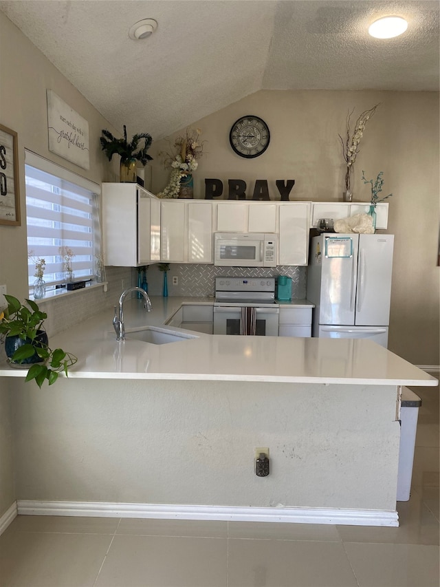 kitchen featuring kitchen peninsula, white appliances, sink, white cabinetry, and lofted ceiling