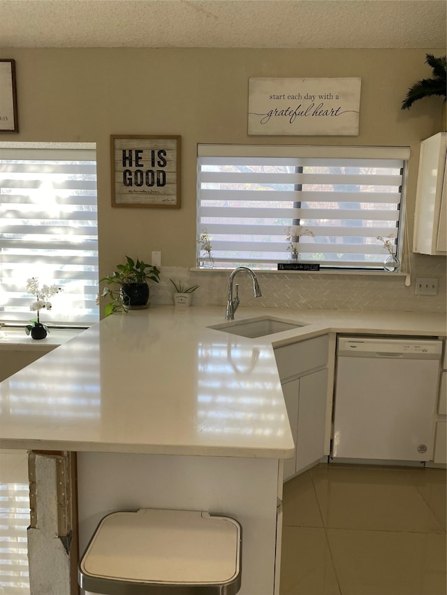 kitchen with dishwasher, sink, a textured ceiling, light tile patterned flooring, and white cabinetry