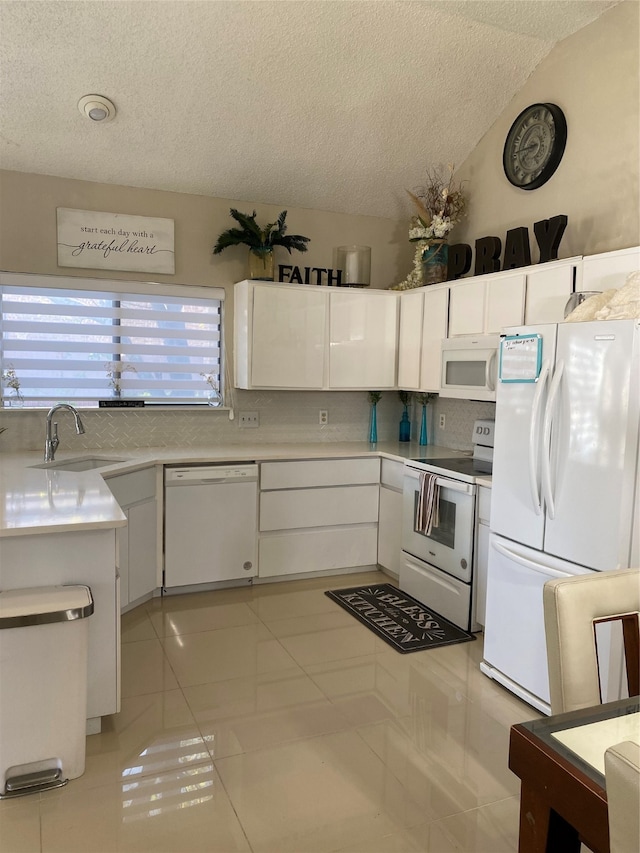 kitchen with white appliances, sink, light tile patterned floors, a textured ceiling, and white cabinetry