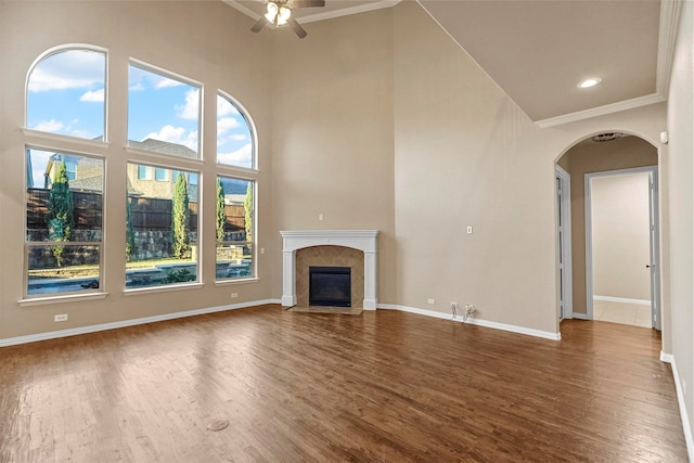 unfurnished living room with crown molding, a towering ceiling, and dark wood-type flooring