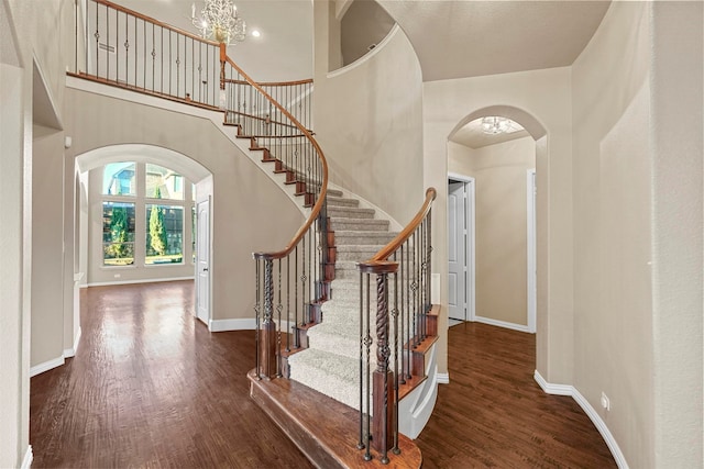 foyer featuring a towering ceiling, dark wood-type flooring, and an inviting chandelier