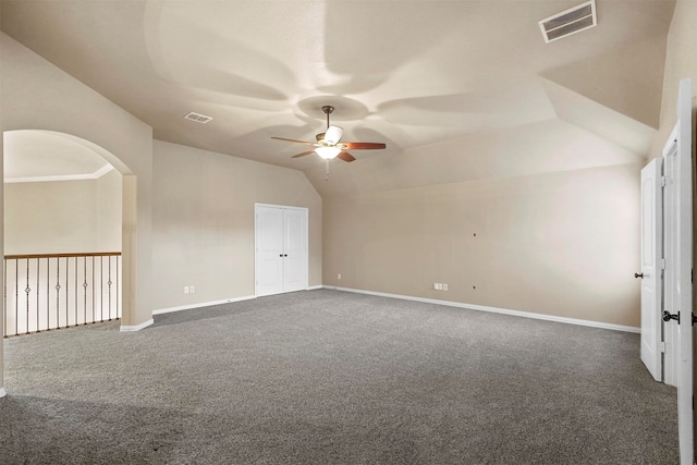 empty room featuring ceiling fan, dark carpet, and vaulted ceiling