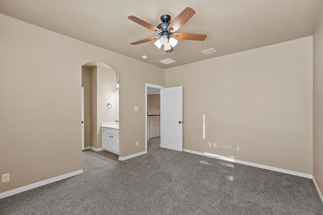 unfurnished bedroom with light carpet, ensuite bathroom, and ceiling fan