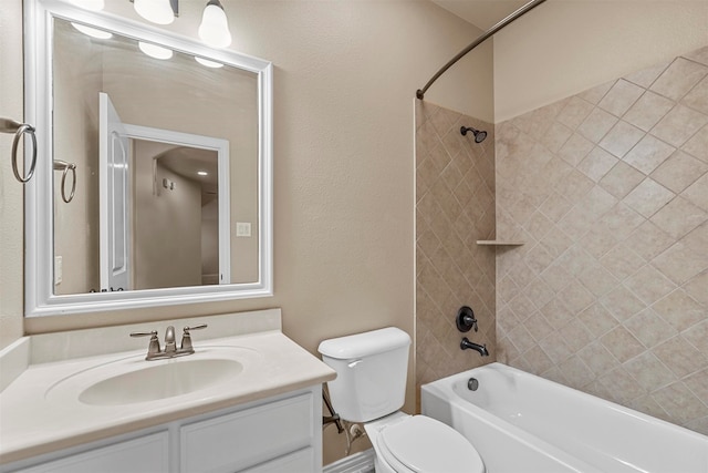 full bathroom featuring tiled shower / bath combo, toilet, and vanity