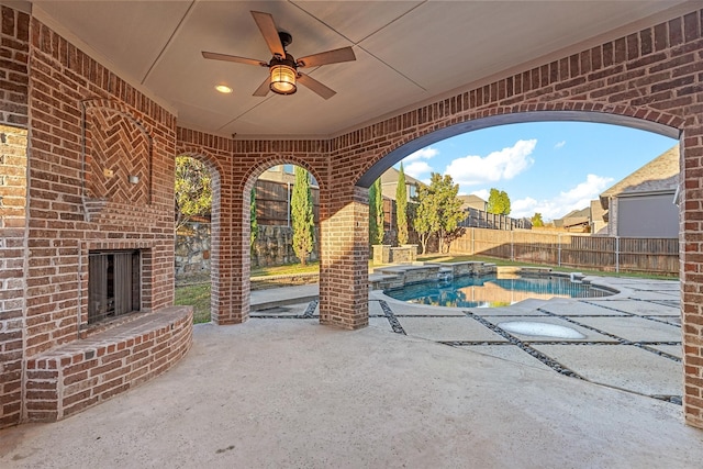 view of patio / terrace featuring an outdoor brick fireplace, ceiling fan, and a fenced in pool