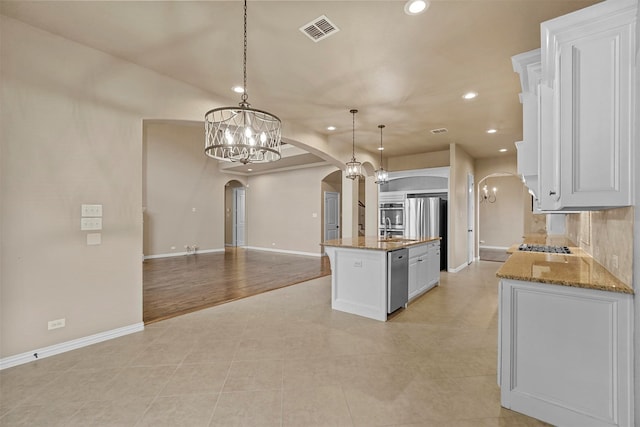 kitchen with pendant lighting, an inviting chandelier, light hardwood / wood-style floors, white cabinetry, and an island with sink