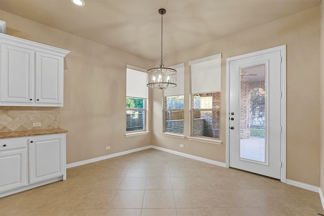 unfurnished dining area with light tile patterned floors, a wealth of natural light, and an inviting chandelier