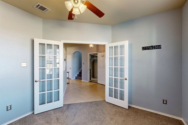 carpeted spare room with ceiling fan and french doors