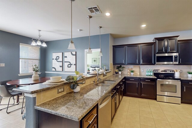 kitchen with hanging light fixtures, sink, appliances with stainless steel finishes, dark brown cabinets, and kitchen peninsula