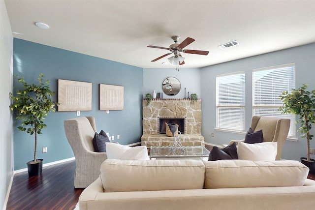 living room featuring a stone fireplace, ceiling fan, and dark wood-type flooring