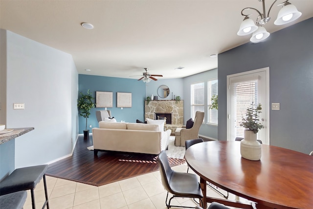 dining space with a fireplace, light hardwood / wood-style flooring, and ceiling fan with notable chandelier