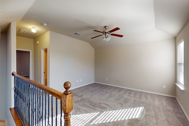 carpeted spare room featuring vaulted ceiling and ceiling fan