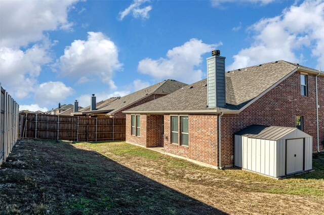 back of house with a yard and a storage shed