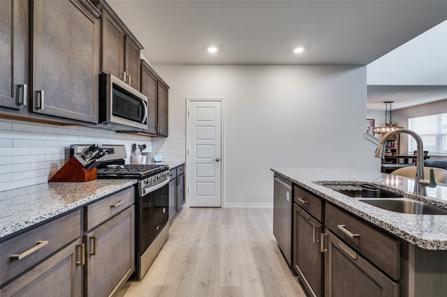 kitchen featuring light stone countertops, sink, stainless steel appliances, dark brown cabinets, and light wood-type flooring