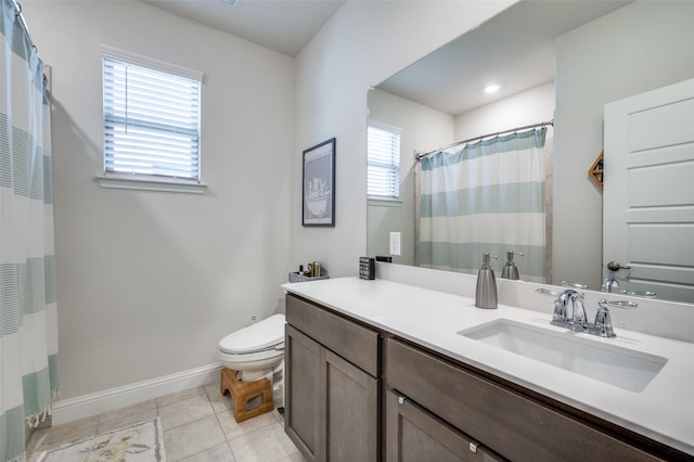 bathroom with a healthy amount of sunlight, toilet, tile patterned flooring, and vanity