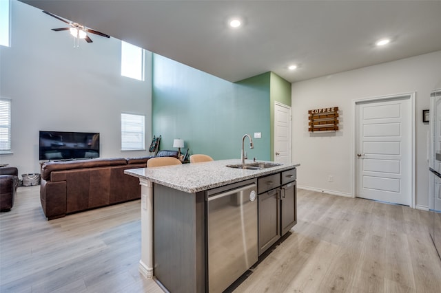 kitchen featuring dishwasher, sink, ceiling fan, an island with sink, and light hardwood / wood-style floors