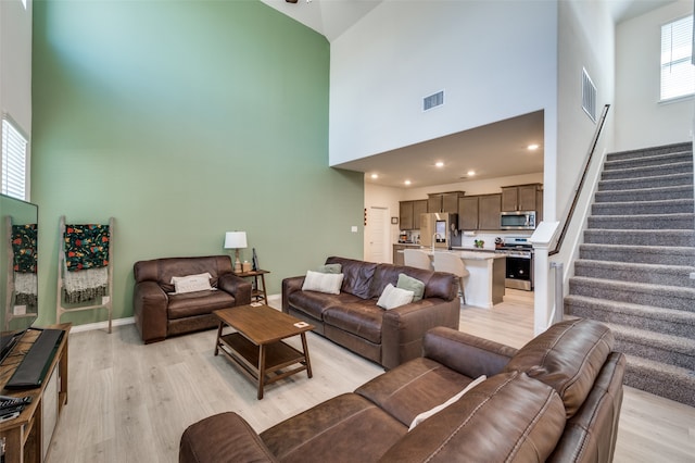 living room with light hardwood / wood-style flooring and a high ceiling