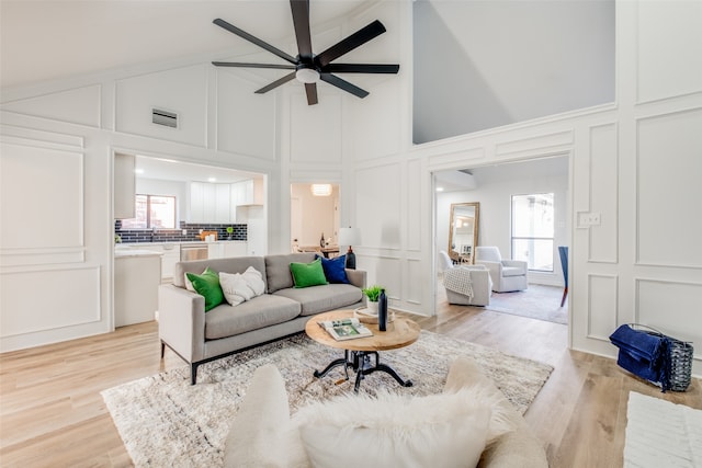 living room featuring ceiling fan, a wealth of natural light, light hardwood / wood-style floors, and high vaulted ceiling