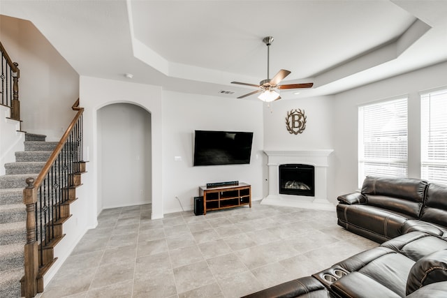 living room with ceiling fan and a raised ceiling