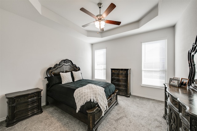 bedroom featuring carpet floors, a tray ceiling, and ceiling fan