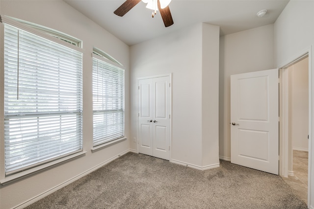 unfurnished bedroom featuring ceiling fan, light carpet, and a closet