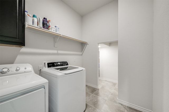 clothes washing area featuring cabinets, light tile patterned floors, and washing machine and clothes dryer