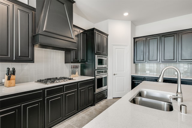 kitchen with premium range hood, sink, light tile patterned floors, tasteful backsplash, and stainless steel appliances